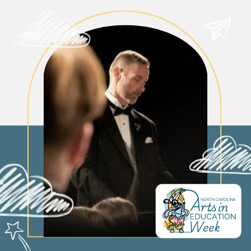 Picture of James Daugherty, a white man with brown and grey and hair and a beard. He is wearing a tuxedo and looking down and to the side.