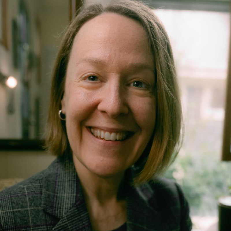 Picture of Vicki Vitiello, a white woman with chin length light brown hair, she is wearing a dark green plaid jacket.