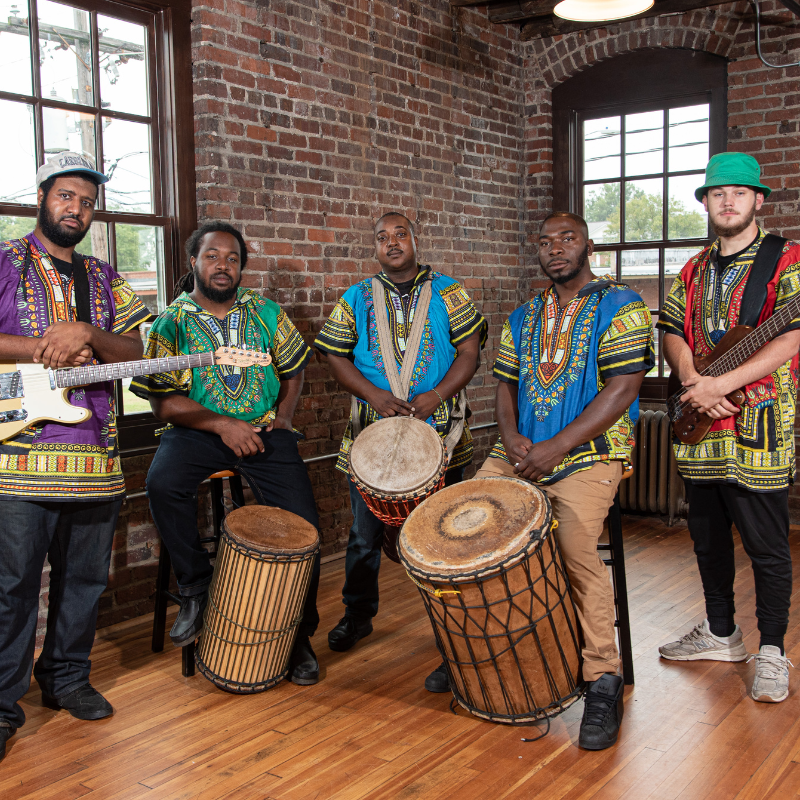 A picture of Africa Unplugged. A group of men wearing African shirts with drums and other instruments